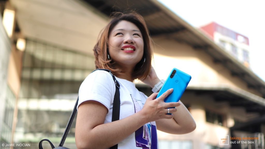 Photo of a woman holding the Realme C3 while in a mall